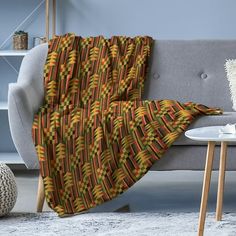 a couch with a blanket on top of it next to a coffee table and lamp