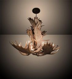 an antler's head chandelier is hanging from the ceiling in front of a gray background