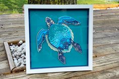 a paper cut turtle in a frame on a wooden table