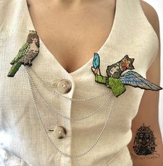 a woman wearing a white shirt with two birds on it's chest and one bird sitting on top of the other