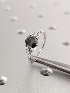 a diamond ring sitting on top of a table next to a pair of tongs