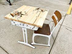 a wooden table and two chairs sitting on the side walk next to a sidewalk in front of a building