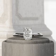 a cushion cut diamond sits on top of a pedestal in front of a pillared wall