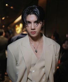 a man with black hair wearing a white suit