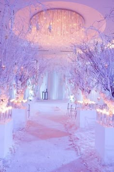 an elegant winter wedding with white and purple decor, candles and flowers on the aisle