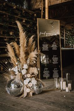 an arrangement of flowers and candles on a wooden floor next to a sign with the names of guests