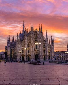 the cathedral is lit up at sunset with pink and purple clouds in the sky behind it