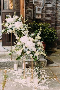 white flowers and candles on the ground in front of a building