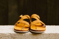 a pair of brown sandals sitting on top of a cement wall