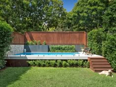 a dog laying on the grass in front of a pool with stairs leading up to it