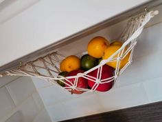 some fruit is in a hammock hanging on the wall above a stove top