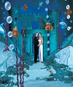 a man and woman are standing in front of an underwater scene with fish, corals and bubbles