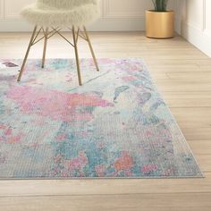 a white chair sitting on top of a wooden floor next to a rug covered in pink and blue flowers