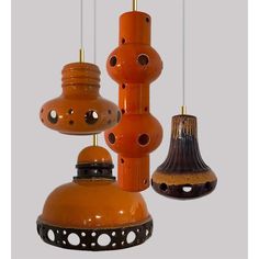 three orange and black hanging lights with holes in the middle one has a bell on it