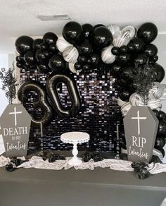 a table topped with black and white balloons, tombstones and crosses on top of it