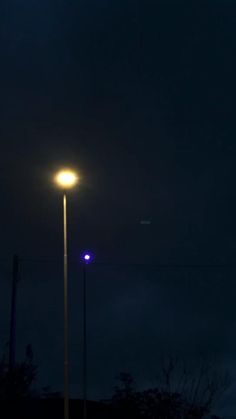 the street light is lit up in the dark night sky with no one on it