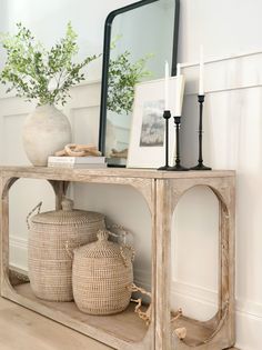 a console table with baskets and a mirror