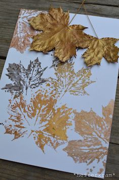 a card with leaves on it sitting on top of a wooden table next to a string