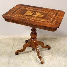 a small wooden table with an intricate design on it's top and legs, sitting on a tile floor