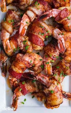 grilled shrimp with bacon and parsley on a white platter, ready to be served