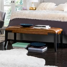 a bed sitting next to a white rug on top of a hard wood floor