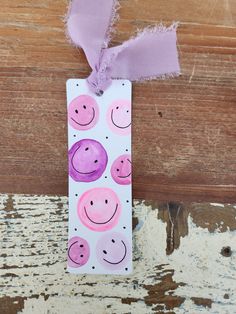 a paper bag with pink and purple smiley faces on it, tied to a piece of wood