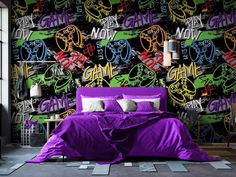 a bedroom with graffiti wallpaper and purple bedspread