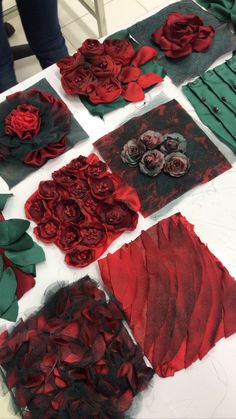 red and green paper flowers are laid out on a table with other pieces of art