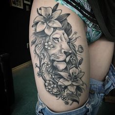 a woman's thigh with a lion and flowers tattoo design on her left leg