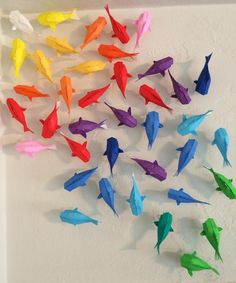 colorful origami fish are arranged on a white wall and placed in the shape of a circle