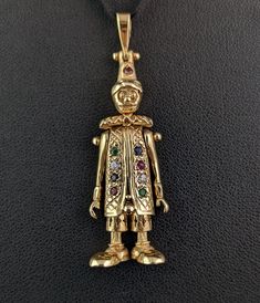 "A fantastic vintage 9ct yellow gold articulated clown pendant.  A classic favourite from the 90s this clown pendant is fully articulated and has movable limbs.  It is set with clear paste, Sapphire, Garnet, Ruby and Emerald stones to the front, down the clowns coat and on the hat. A great novelty piece, a good sized pendant full of cheer, these look great hung from a nice vintage yellow gold chain and make for a wonderful gift. The pendant has a large integral gold bale which is hallmarked. Marks and era: Fully hallmarked for 9ct gold, London Assay office, 1993. Condition: Good used overall with minor signs of age and use, some light surface wear.  Approx measurements: 2.10\" length  0.60\" width  8.74 grams total weight  Any questions or queries please contact us. FREE WORLDWIDE SHIPPING Antique Gold Necklace With Vintage Charm For Collectors, Vintage 14k Gold Pendant Charms, Clown Necklace, Victorian Gold Pendant Charms, Gold Steampunk Necklace Vintage, Emerald Stone, Yellow Gold Chain, Vintage Yellow, Aging Signs