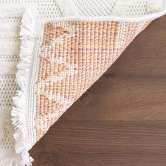 an orange and white rug on top of a wooden floor next to a wood floor