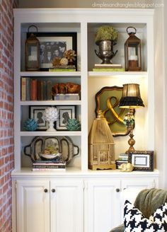 a living room filled with lots of furniture next to a wall mounted book shelf and lamp