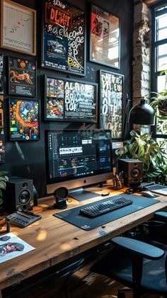 a desk with a computer and speakers on it in front of a window filled with posters