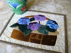 a potted plant sitting on top of a table next to a vase filled with purple flowers