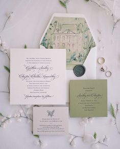 the wedding stationery is laid out on top of the table with flowers and greenery