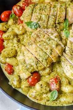 a pan filled with meat and vegetables covered in pesto sauce