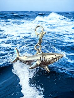 a shark keychain floating on top of a wave in the ocean with water splashing around it