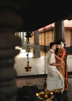 a man and woman standing next to each other in front of a building with candles