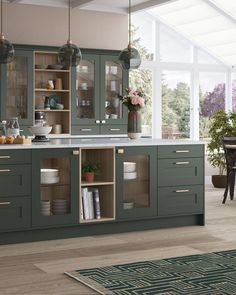 a large kitchen with green cabinets and white counter tops, an area rug on the floor