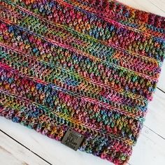 a multicolored crocheted scarf sitting on top of a wooden floor