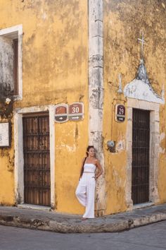 a woman standing in front of a yellow building