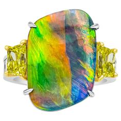 A one-of-a-kind fashion ring, showcasing a GIA certified 5.75 carats black natural opal with a freeform shape and no indications of heat treatment, set on an extremely rare prong setting. Flanked by two fancy yellow trapezoid cut diamonds with vivid yellow color and VS1 clarity. Accented by channel-set princess cut diamonds weighing 1.20 carats total with F-G color and VS clarity on the shank. Made with 18K yellow gold and platinum. Size 6 US, resizable upon request. Fancy Yellow Diamond Ring, Mens Rings Fashion, Yellow Diamond Rings, Diamond Fashion Rings, Contemporary Ring, Modern Ring, Green Diamond, Fashion Ring, Diamond Fashion