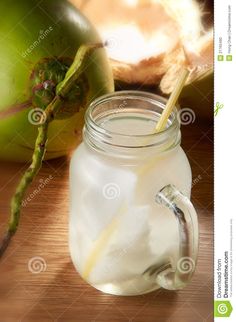 a glass jar filled with liquid sitting on top of a table next to an apple