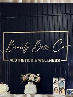 a vase with flowers on top of it next to a sign that says beauty boss cat aesthetics and wellness