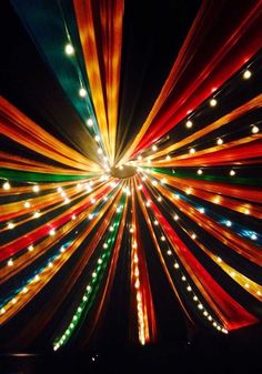 an image of colorful lights in the night sky with long ribbons hanging from it's ceiling