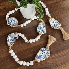 a blue and white beaded necklace with tassels next to a potted plant