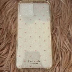 an iphone case with pink and white flowers on it sitting on top of a furry surface