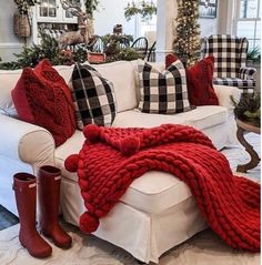 a living room filled with white furniture and red blankets on top of the couches