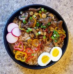 a bowl filled with noodles, meat and veggies next to an boiled egg